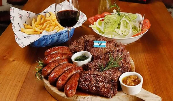 Parrilla para compartir de Los Ches — cortes, chorizos, papas y ensalada