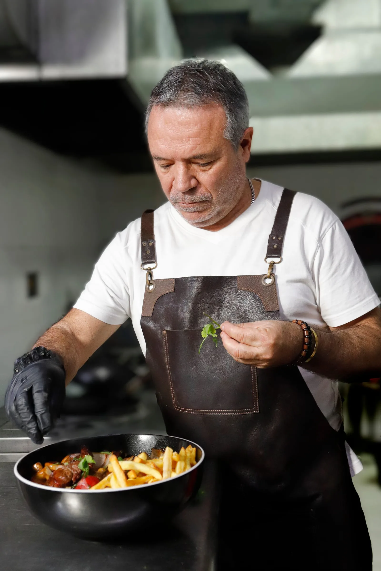 El chef de Los Ches emplatando un salteado — el toque final de cilantro